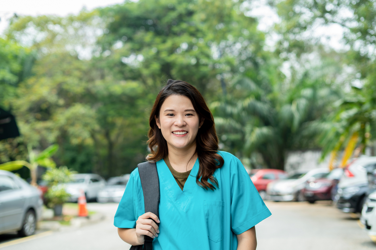 Female health professional smiling at the camera in the hospital car park